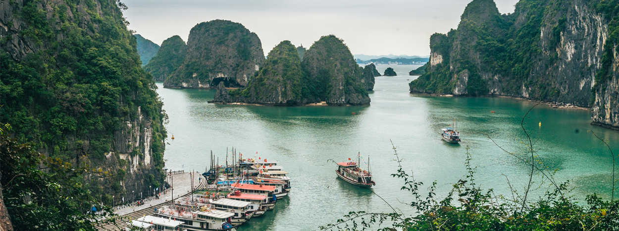 Vista panorámica de la Bahía de Ha Long en Vietnam, con barcos tradicionales navegando entre islas kársticas, como parte del itinerario del viaje en grupo de Viajes Himba.