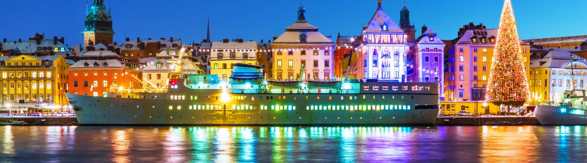 Grupo de amigos brindando con copas de champán en una plaza nevada de Estocolmo durante el Fin de Año, con edificios históricos iluminados y fuegos artificiales de fondo.