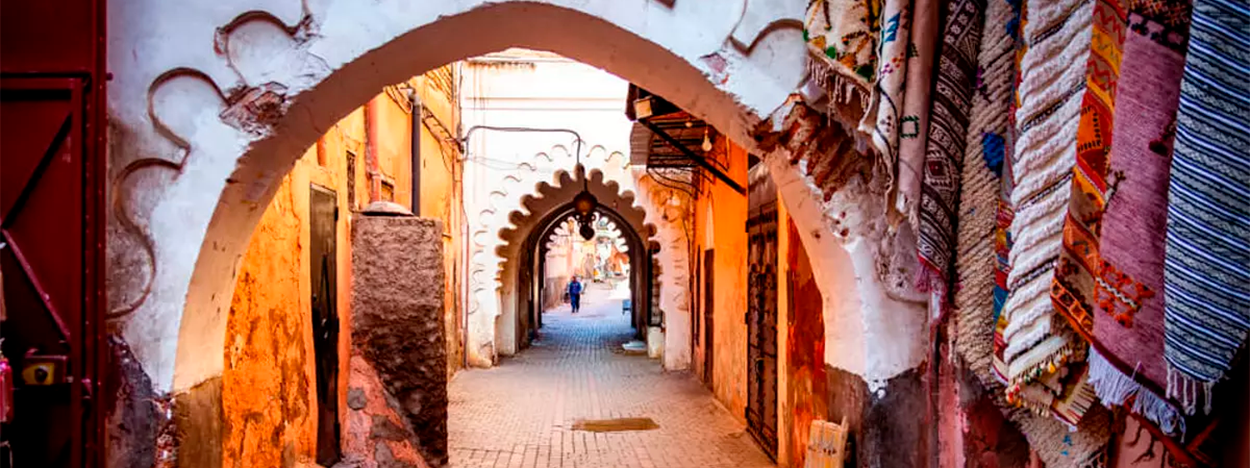 Grupo de viajeros singles a Marruecos montando en dromedario en el desierto de Erfoud al atardecer.